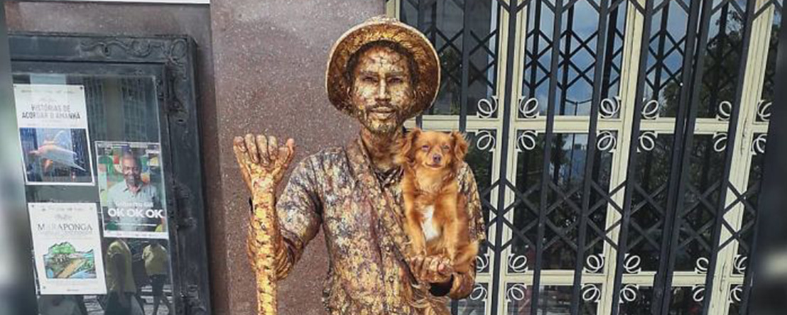 Perrita ayuda a su papá, un artista callejero en su rutina de estatua humana